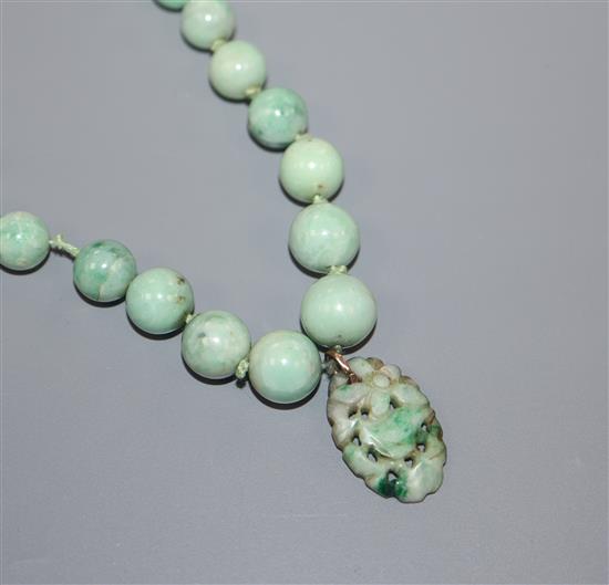 A single strand graduated jadeite bead necklace with carved pendant drop and 9ct clasp, 62cm.